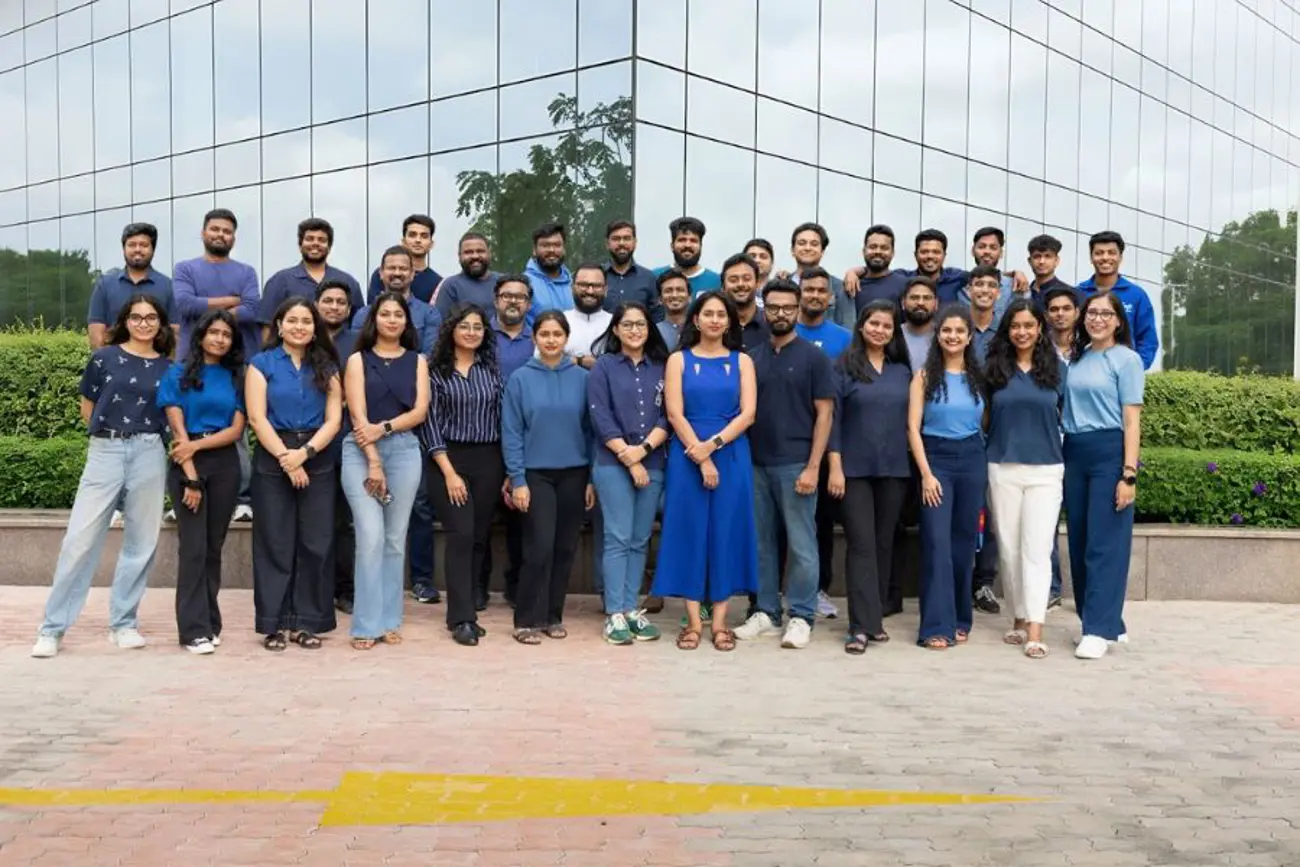 A large group of people posing for a photo in front of a modern glass office building