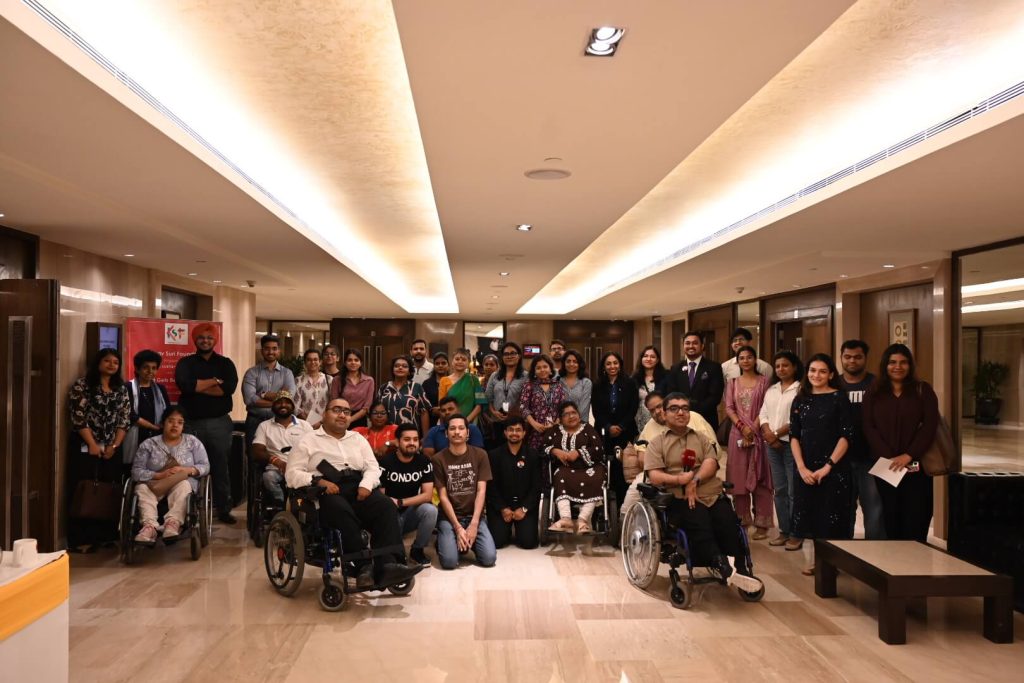 A diverse group of people, including wheelchair users, posing for a photo in a hallway.