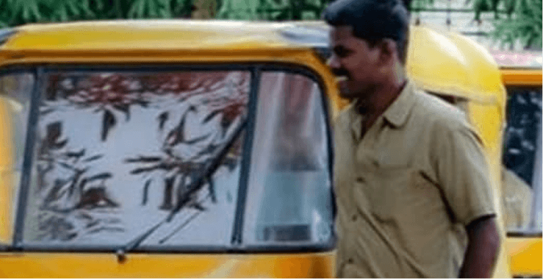 Person standing beside an auto-rickshaw.