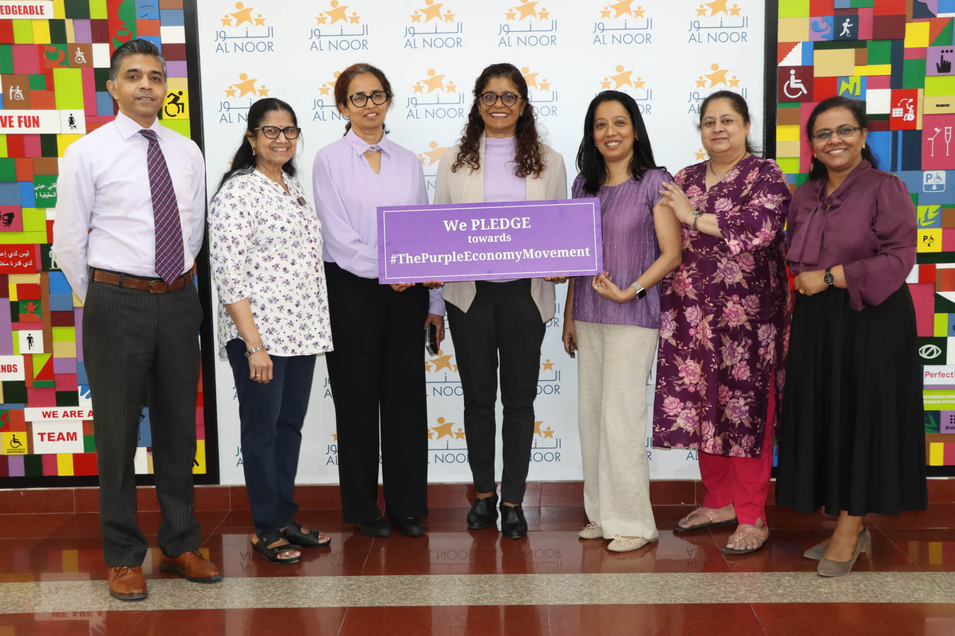 Group holding a Purple Economy pledge sign at an Al Noor event.